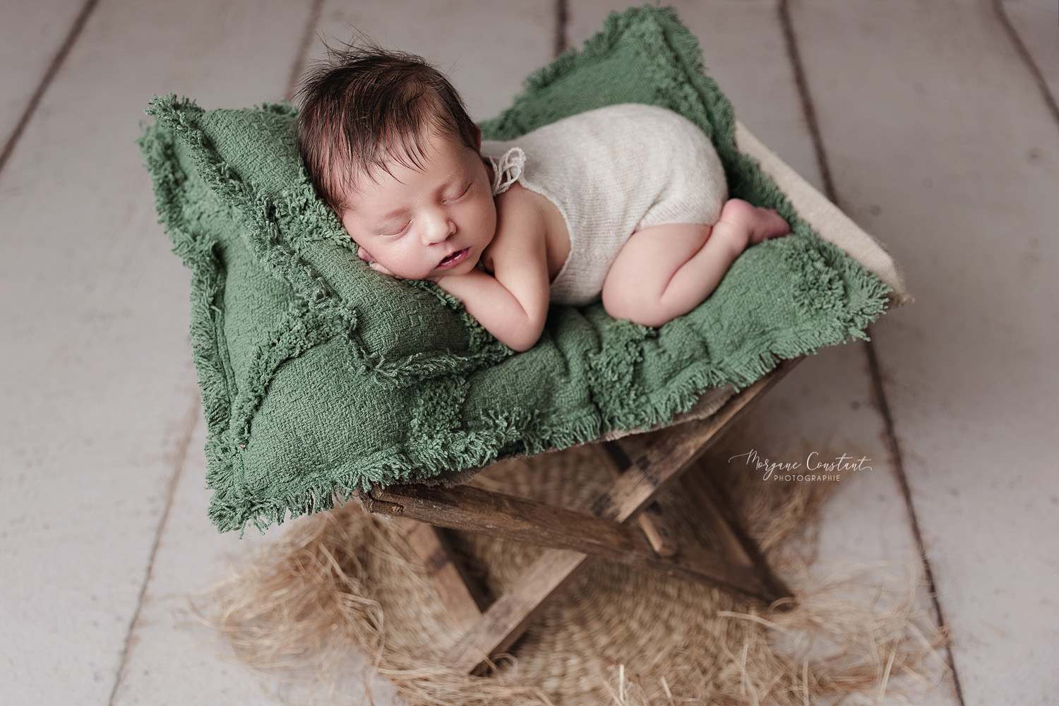 Bébé endormi dans un transat en bois avec un matelas vert